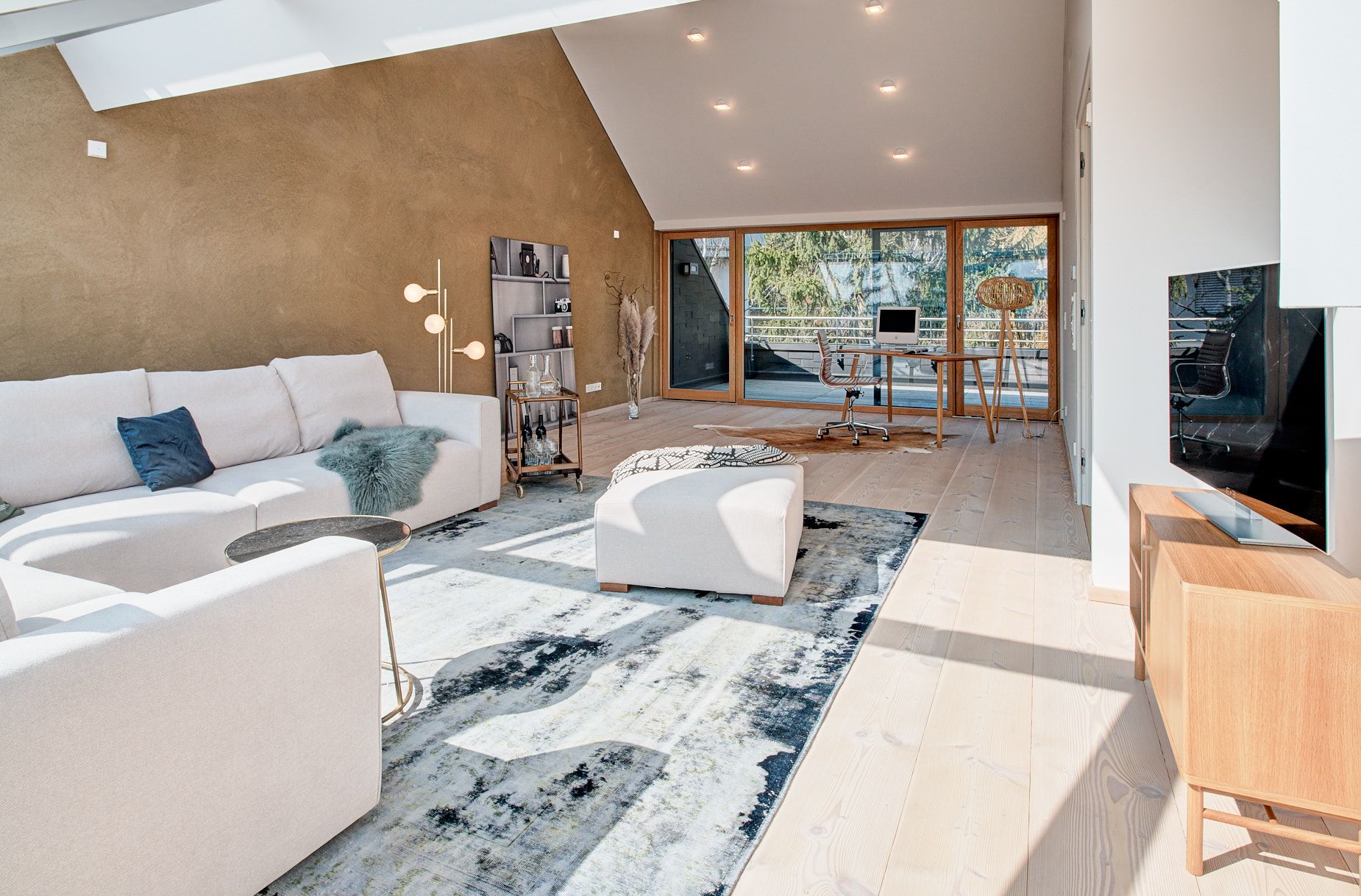 Wohnraum im Dach mit Lehmwand und großem L-Sofa in beige und blauem Teppich