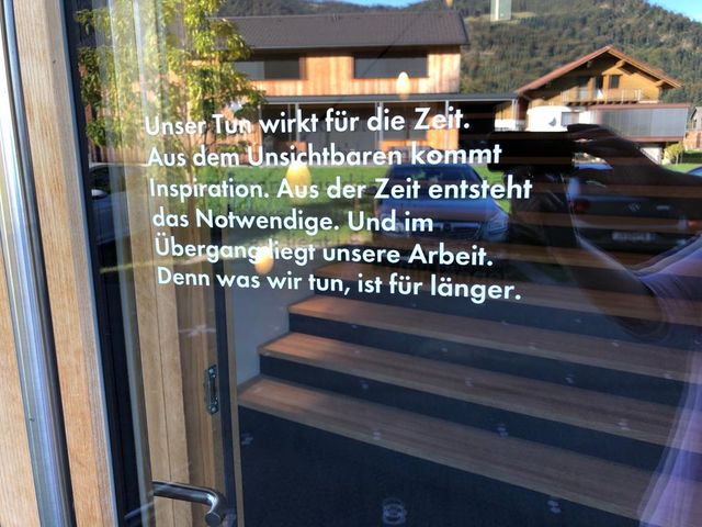 Spruch an der Tür: unser Tun wirkt für die Zeit. Aus dem Unsichtbaren kommt Inspiration. Aus der Zeit entsteht das Notwendige. Und im Übergang liegt unsere Arbeit. Denn was wir tun, ist für länger.