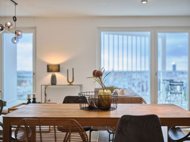 Blick vom Esstisch über den Wohnbereich Richtung Terrasse - mit Weitblick über Wien - auf der Konsole eine Tischleuchte
