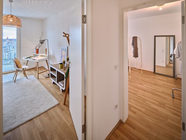 Blick vom Gang Richtung Arbeitszimmer und danebenliegendem Schlafzimmer - kleiner Home Office Bereich mit Schreibtisch und Stuhl, daneben Standgarderobe mit Deko