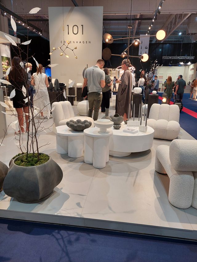 großer Messestand von 101 Copenhagen mit schwarzen mehrarmigen Deckenleuchten aus Metall und großen, gemütlichen Sofalandschaften in creme