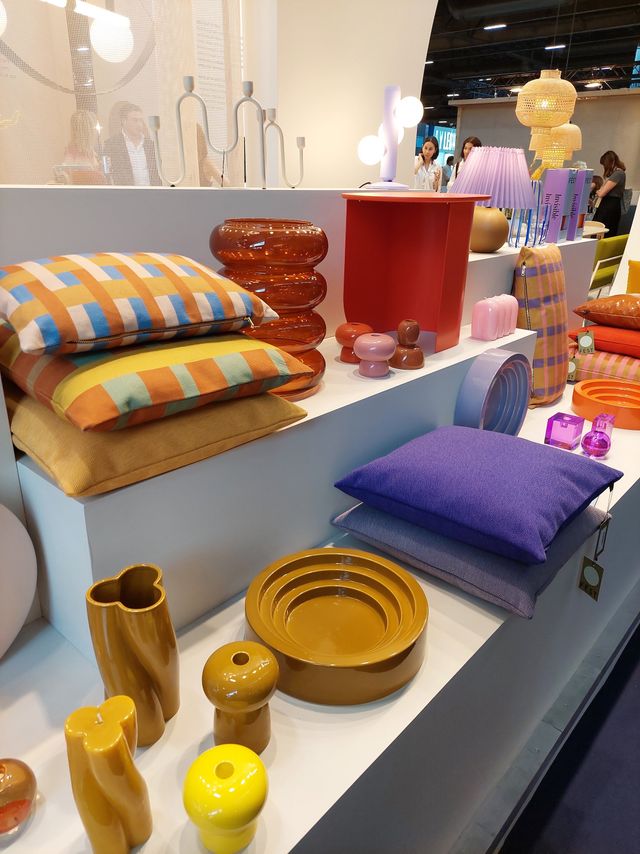 Arrangement aus Kissen und Geschirr in kräftigen Orange, Senf- und Violett-Tönen