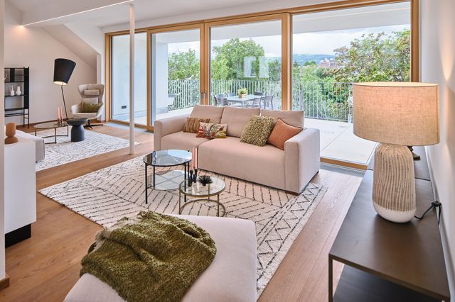 Blick ins Wohnzimmer mit Terrasse dahinter - cremefarbenes Modulsofa schwarze Konsole heller Teppich Tischleuchte und Couchtisch-Set