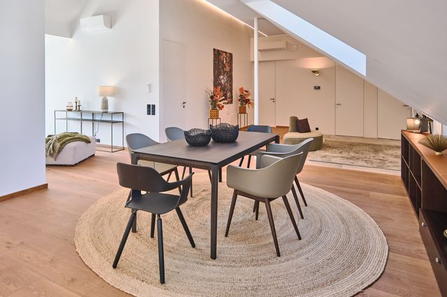 offener Essplatz mit Blick in den Eingangsbereich, dunkler Holztisch mit abgerundeten Ecken, olivgrüne Designstühle mit dunklen Holzbeinen, Sisalteppich, langes Sideboard aus dunklem Holz