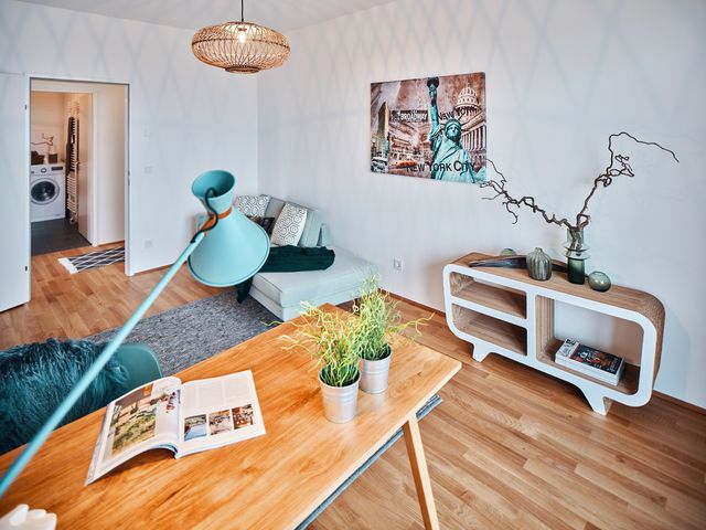 Home Office mit Eichenschreibtisch, mintfarbener Schreibtischleuchte, Sideboard aus Pappe und mintgrünem Sofa sowie modernem NewYork Bild und Rattanhängeleuchte oval