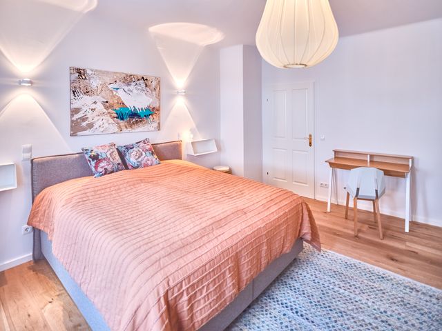 Boxspringbett, Schreibtisch mit Stuhl, Wandregalen, Wandleuchten und moderner Kunst